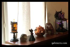 bookshelf with decorations on top--cute cat witch, metal jack o' lantern